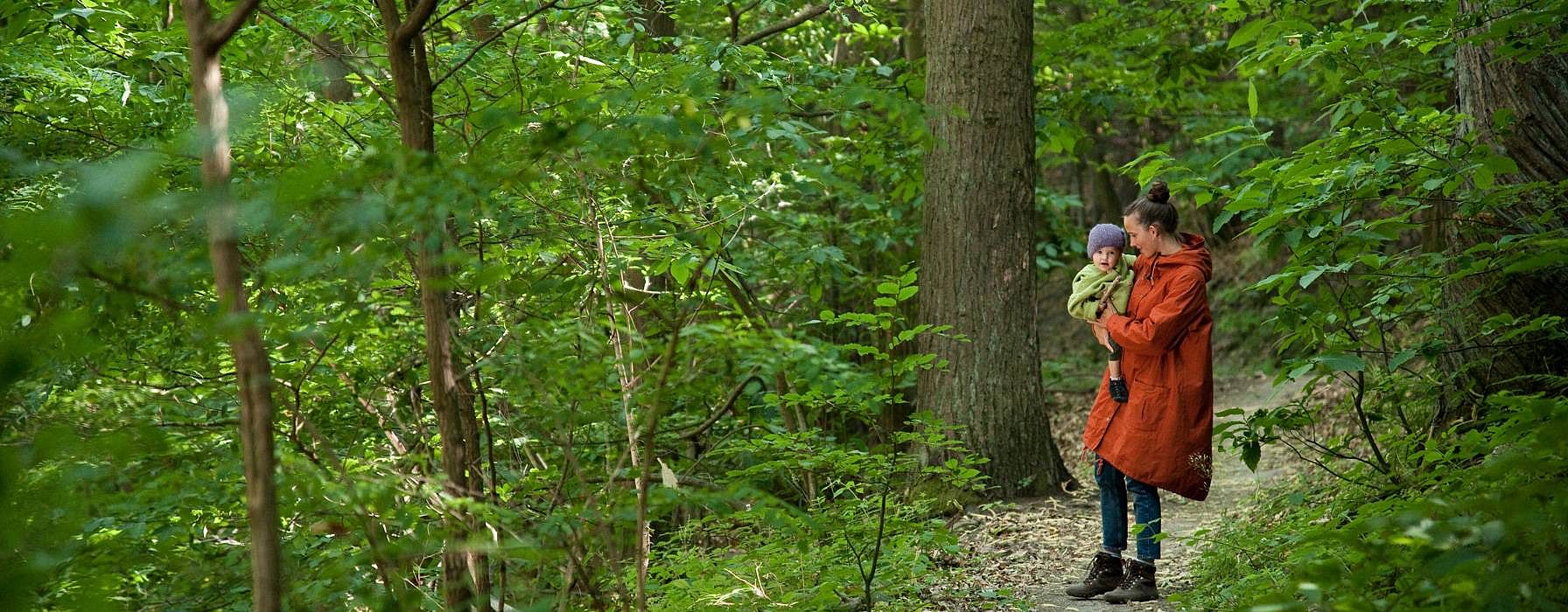 Donna tiene in braccio un bambino in un bosco
