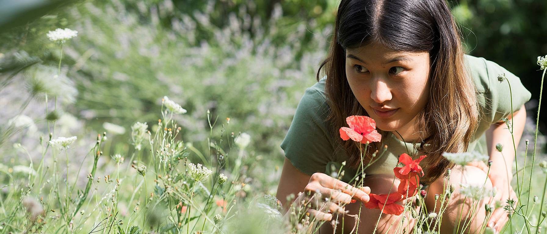 ragazza in un campo che annusa un papavero