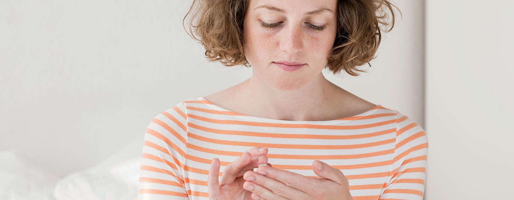 Una giovane donna ha in mano una piccola quantità di crema che sta per applicare