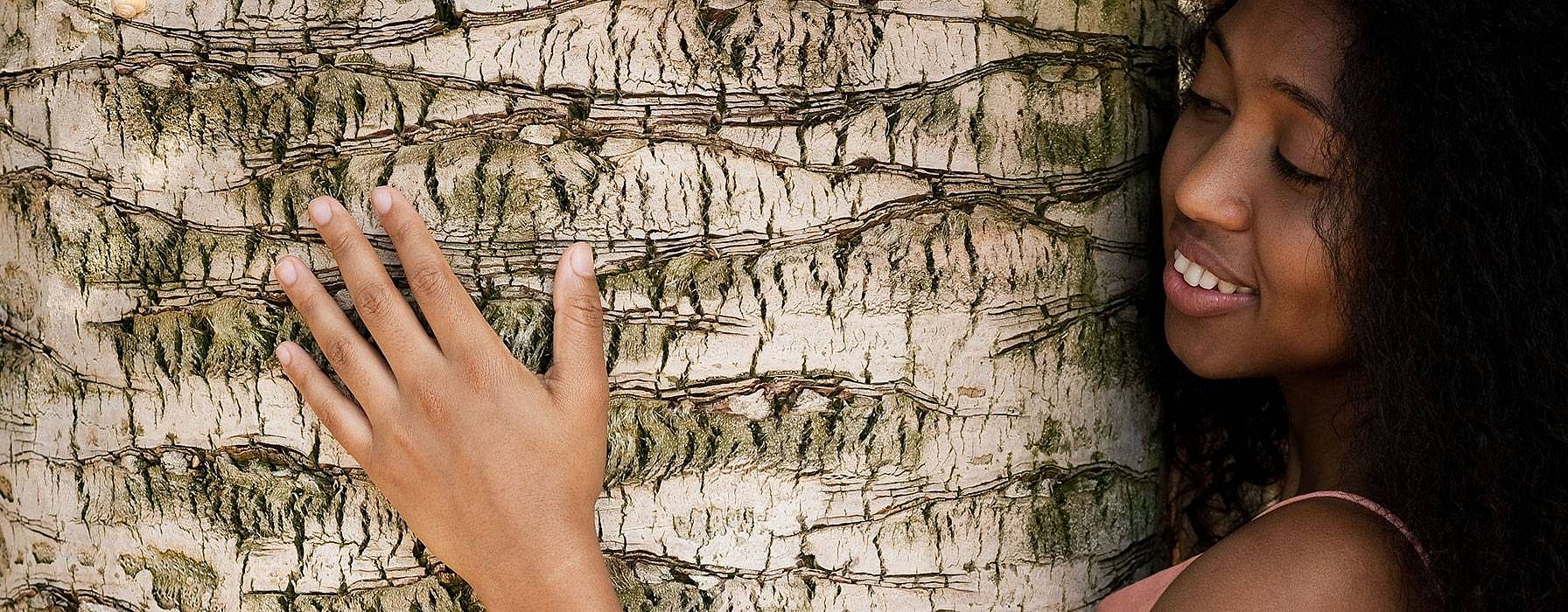Donna riccia e mora abbraccia un albero