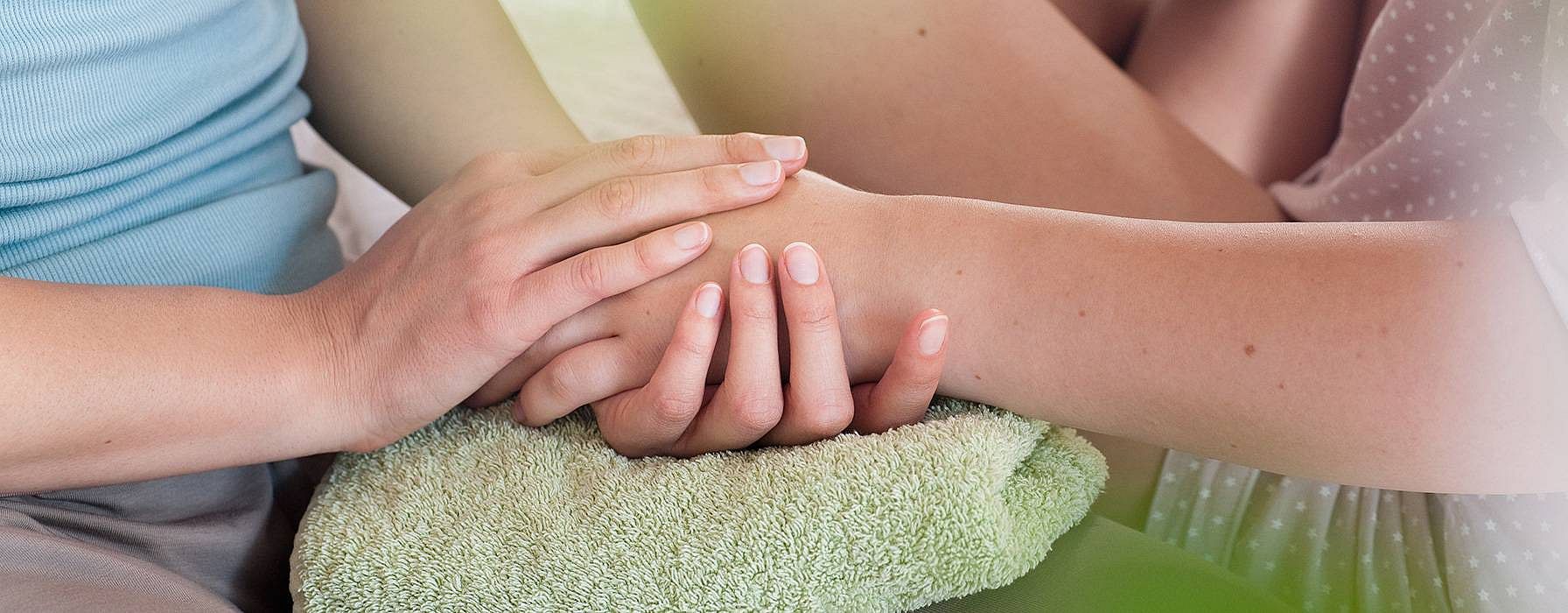 Donna tiene delicatamente la mano di un'altra donna tra le sue mani
