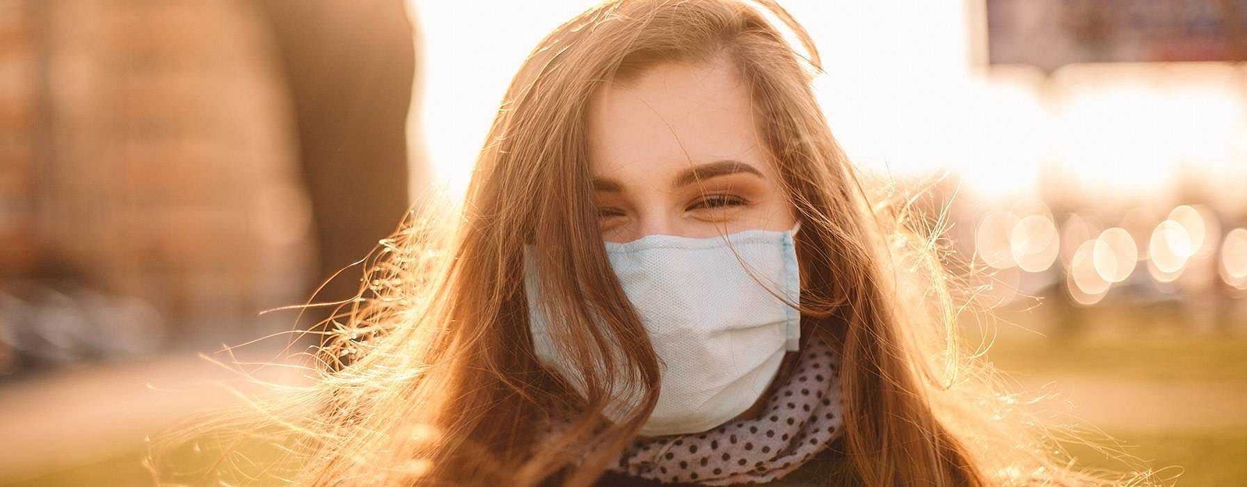 Donna con mascherina sorride mentre c'è il sole