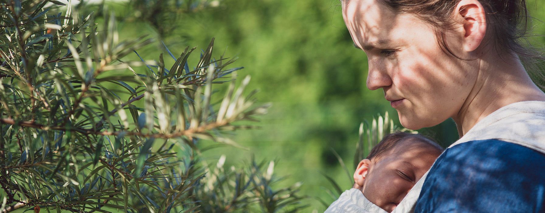 Mamma tiene il bambino in una fascia mentre è all'aria aperta