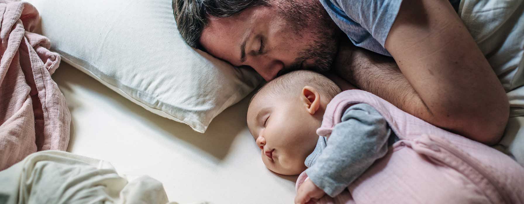papà e neonato dormono nel letto