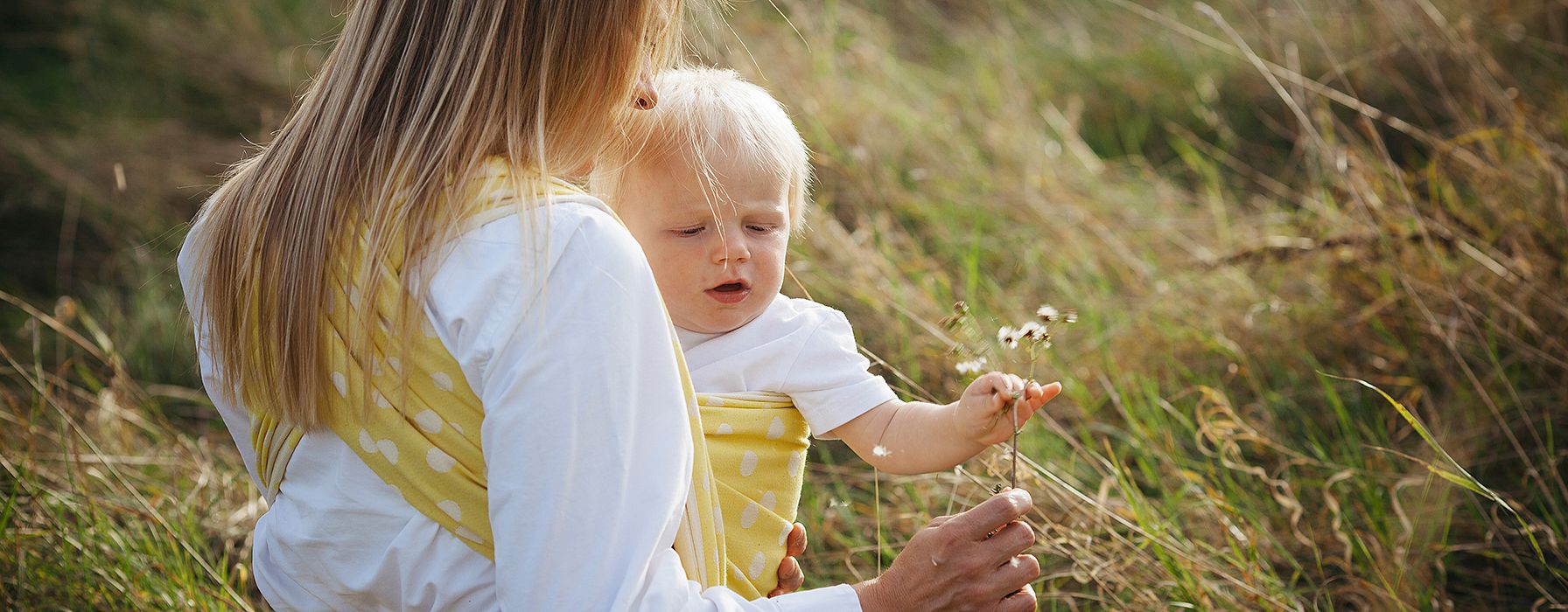 Mamma e figlio in braccio mentre tiene un fiore in mano in un campo