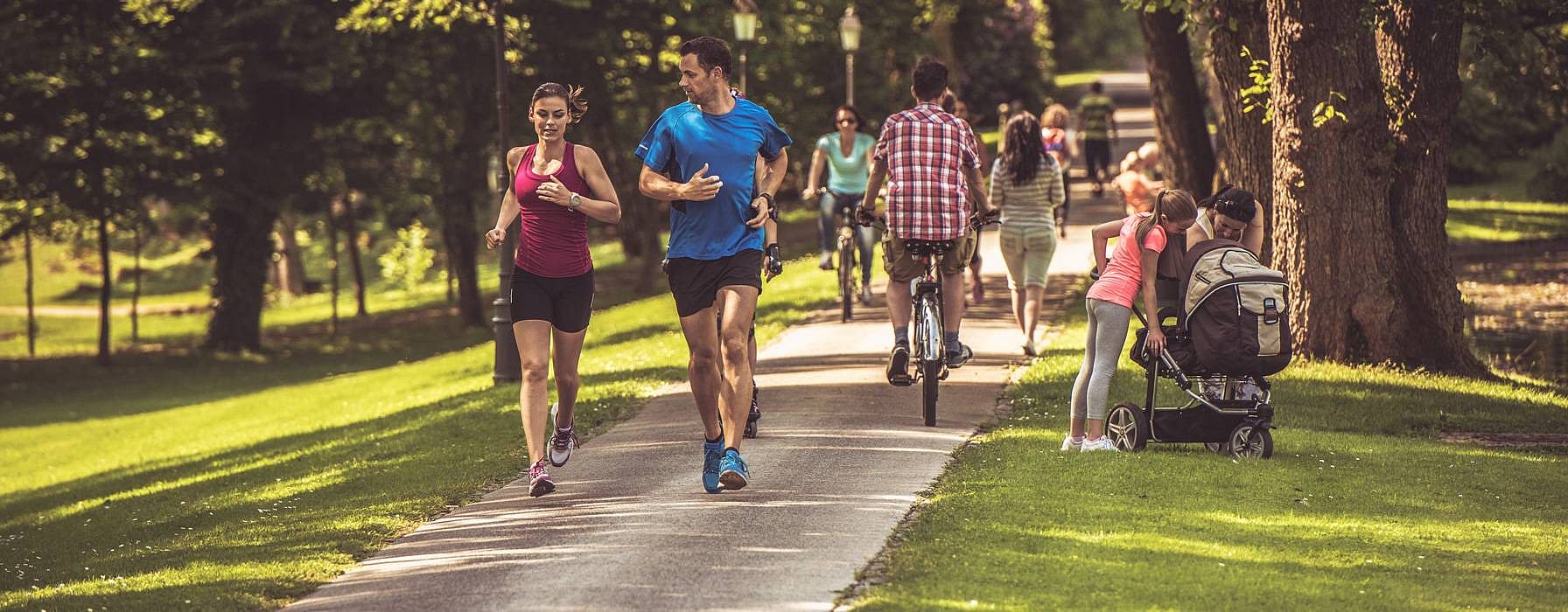 Insieme di sportivi che corrono all'aperto in un parco