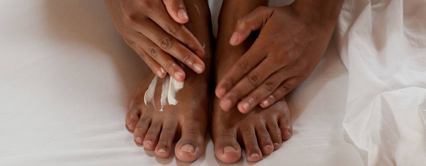 Due mani applicano la crema su due piedi