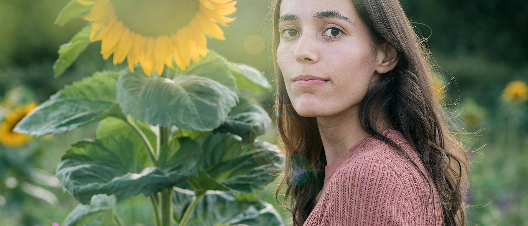 La donna si trova di fronte a un grande girasole