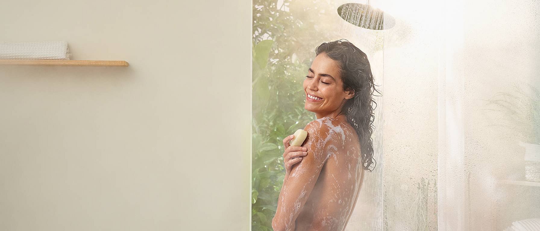 La donna usa il sapone sotto la doccia