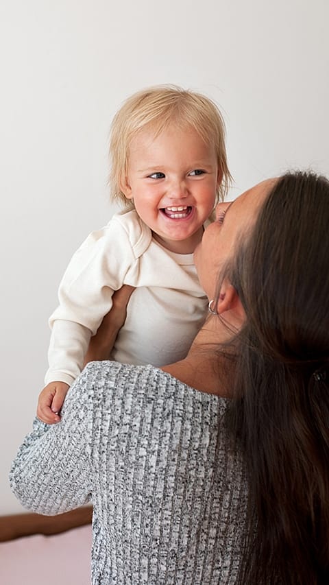 Bambino viene preso in braccio dalla mamma e sorride