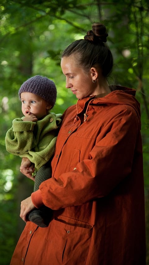 Donna tiene in braccio un bambino nel bosco