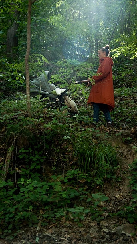 Donna con passeggino in un bosco