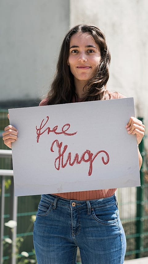 una ragazza tiene in mano un cartello con scritto 