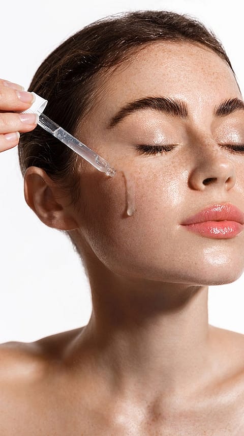 Donna con occhi chiusi applica il siero sul viso