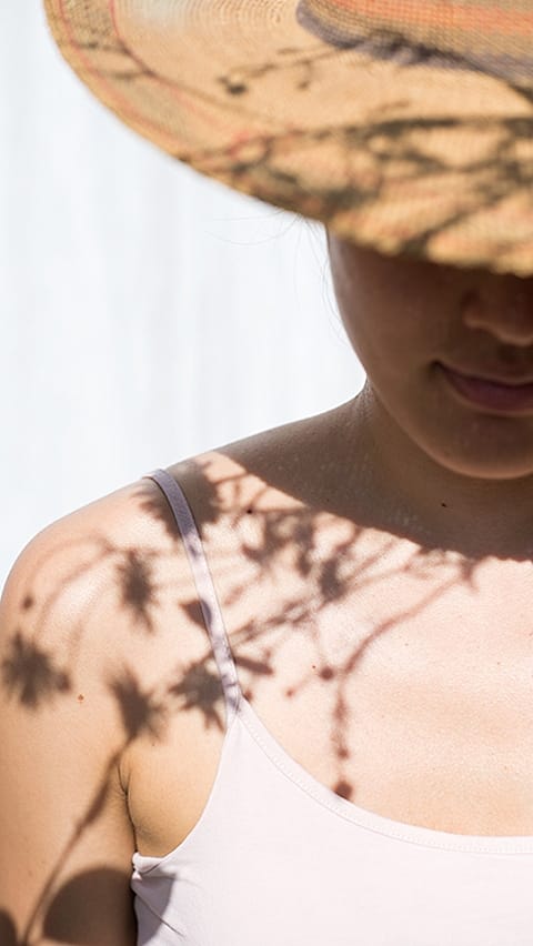 Donna in un cappello con un modello di ombra di un fiore