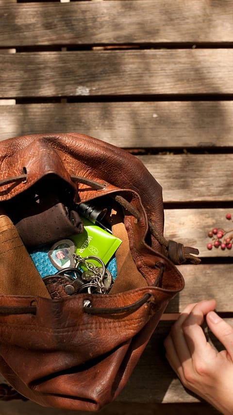 Borsa di donna poggiata a terra semiaperta con chiavi e crema nutriente skin food