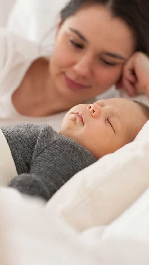 Mamma guarda il suo neonato mentre dorme