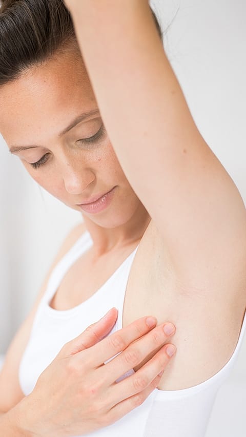 Donna applica il deodorante tenendo il braccio alzato