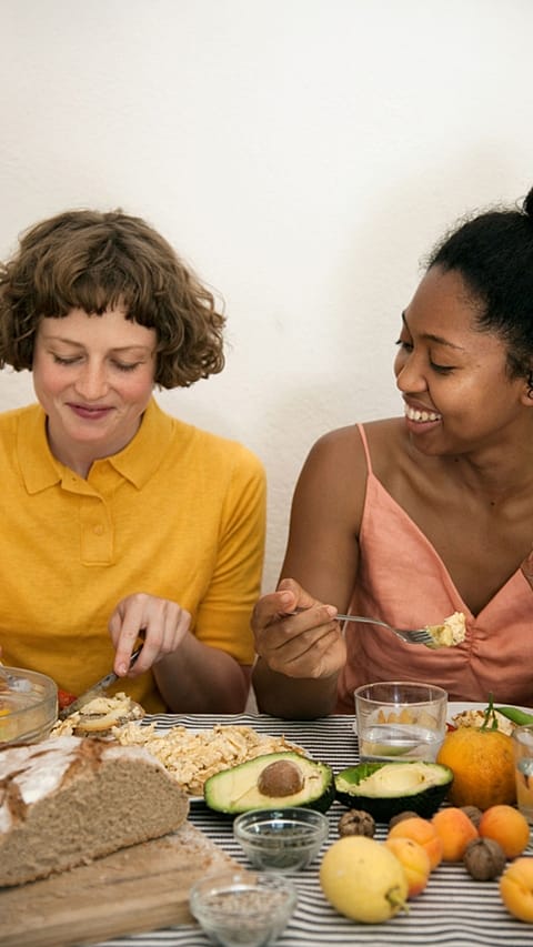 due ragazze sedute a tavola che mangiano