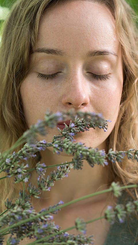 Ragazza annusa la lavanda con gli occhi chiusi