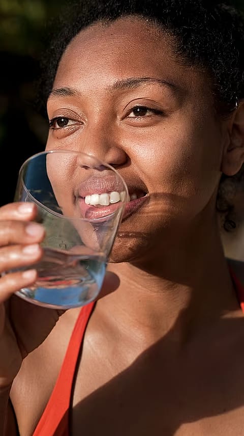 Donna che beve da un bicchiere d'acqua