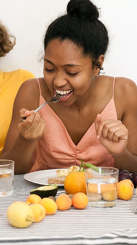 Donna seduta a tavola che mangia cibo sano