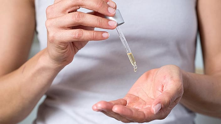 Pipetta gocciola olio su una mano