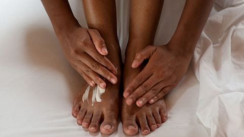 Due mani applicano la crema su due piedi
