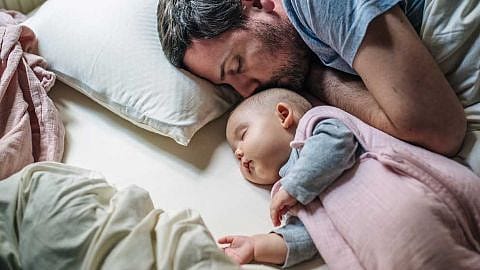 papà e neonato dormono nel letto