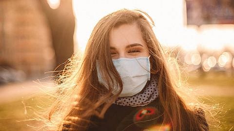 Donna con mascherina sorride mentre c'è il sole