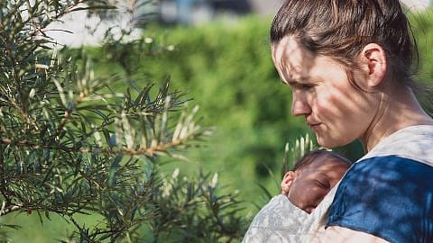 Mamma tiene il bambino in una fascia mentre è all'aria aperta