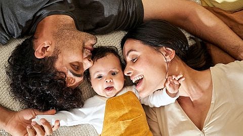 Mamma e papà e bimbo neonato sdraiati sorridono e si guardano