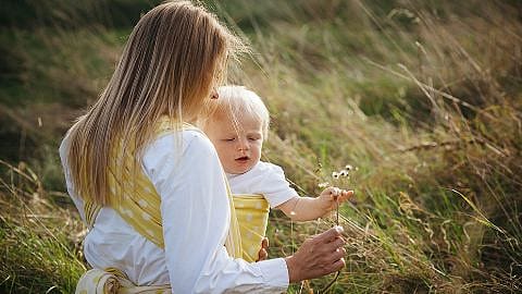 Mamma e figlio in braccio mentre tiene un fiore in mano in un campo