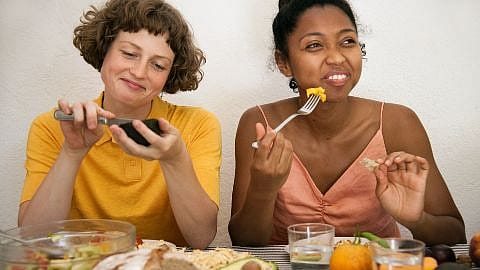 due ragazze: una mangia un avocado con un coltello, l'altra l'ananas con una forchetta