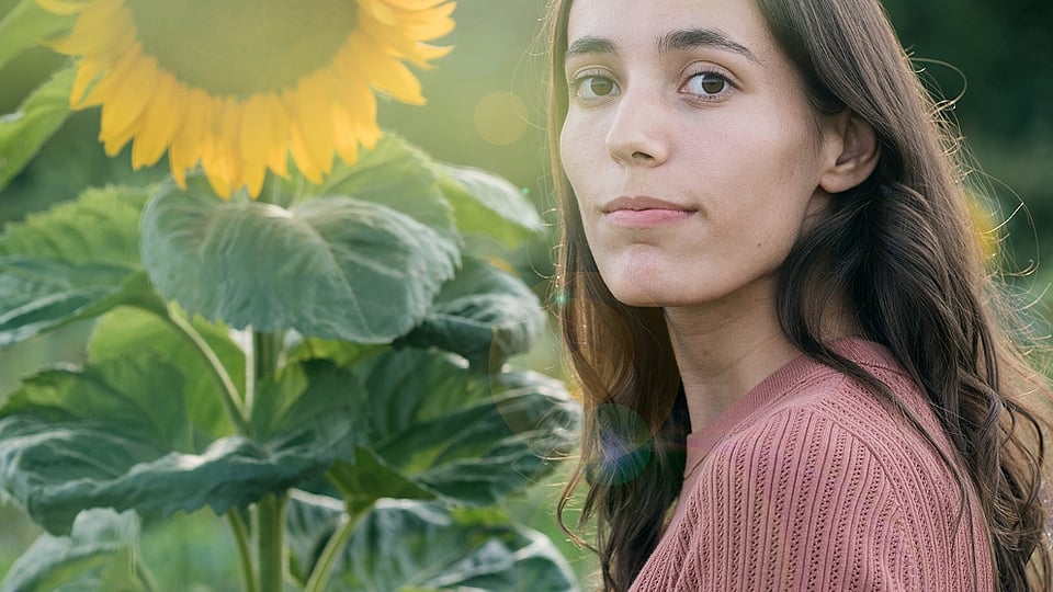 La donna si trova di fronte a un grande girasole