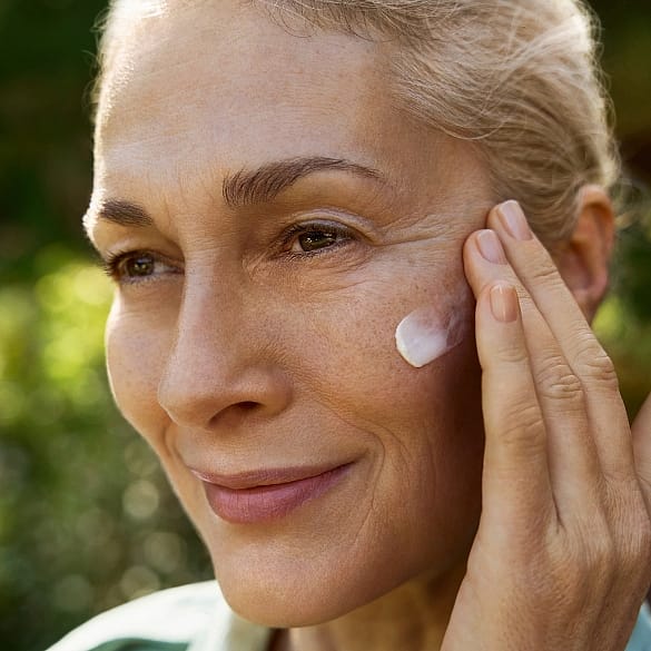 donna che applica la crema viso