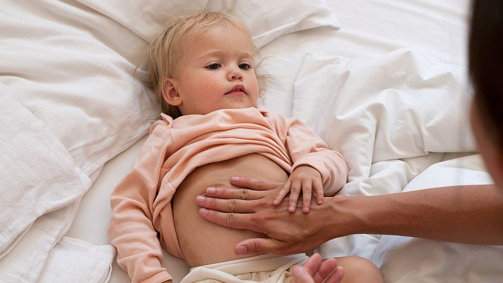 Bambino biondo sdraiato con la mano della mamma sulla pancia