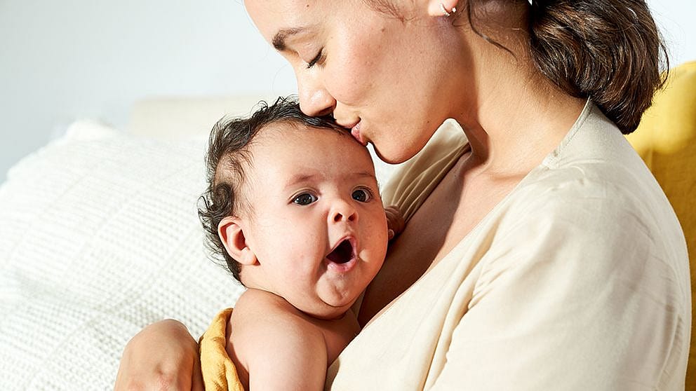 Mamma da un bacio sulla testa del neonato