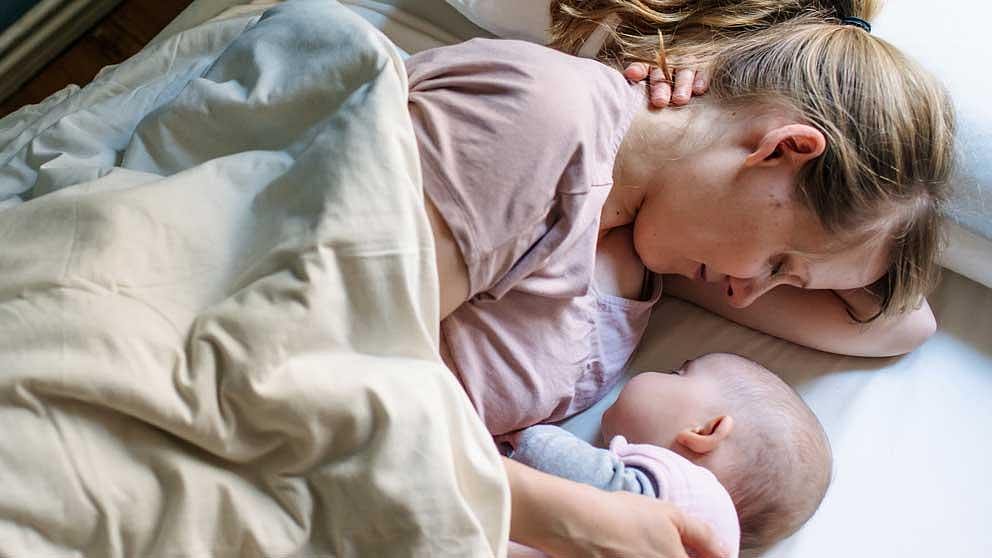 Mamma e neonato dormono nel letto sotto le coperte
