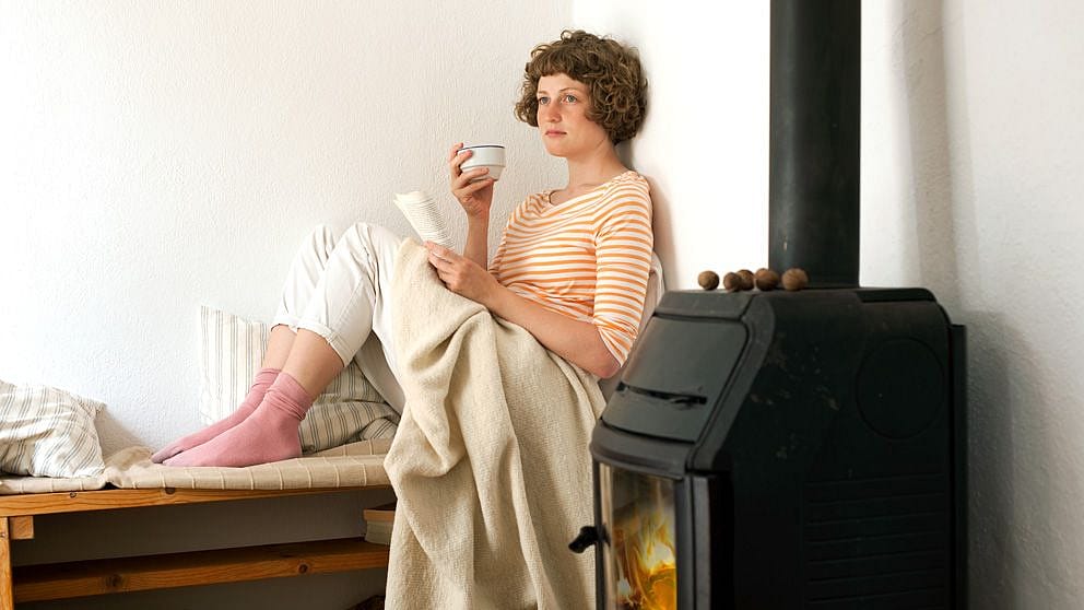 Donna sorseggia il caffè a letto mentre legge un libro