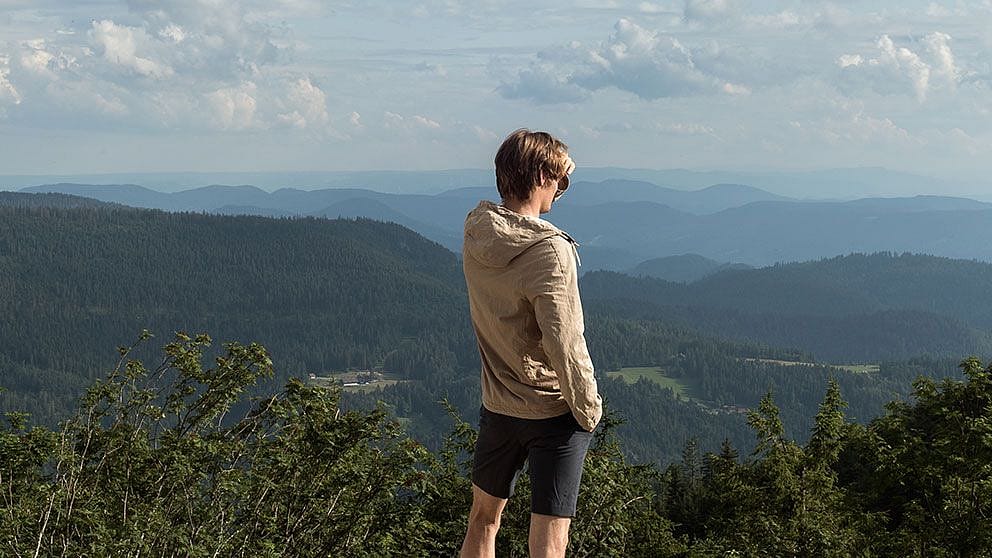 uomo che scruta l'orizzonte in un ambiente montano estivo