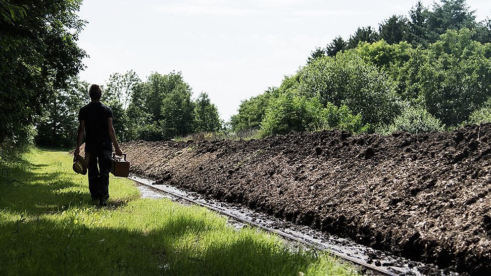 uomo che passeggia portando cassetta attrezzi per lavorare la terra
